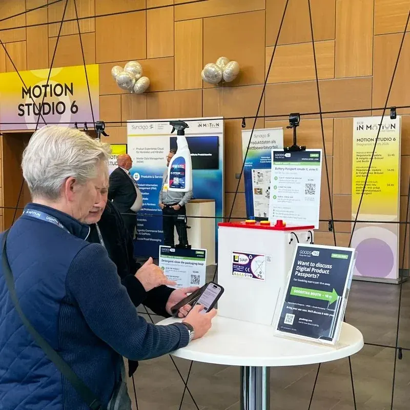 Visitors at ECR iN Motion scanning the QR code of the GoodsTag battery DPP demo, next to a SIAP battery on a display stand